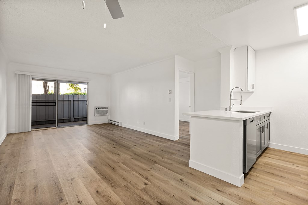 A kitchen with a white counter and wooden floors.