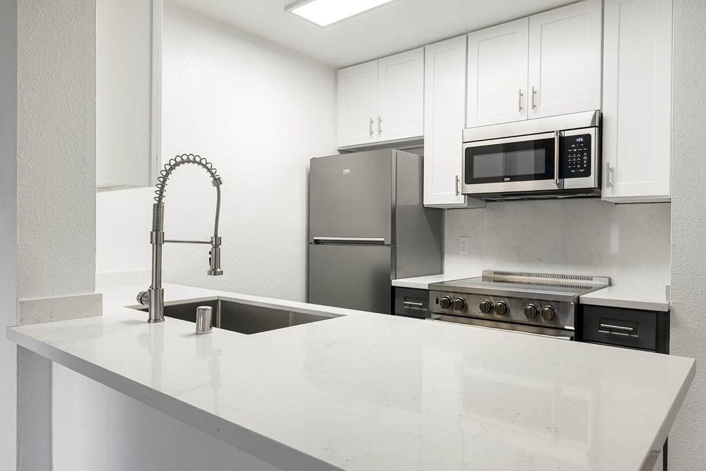 A kitchen with a sink, stove, and microwave.