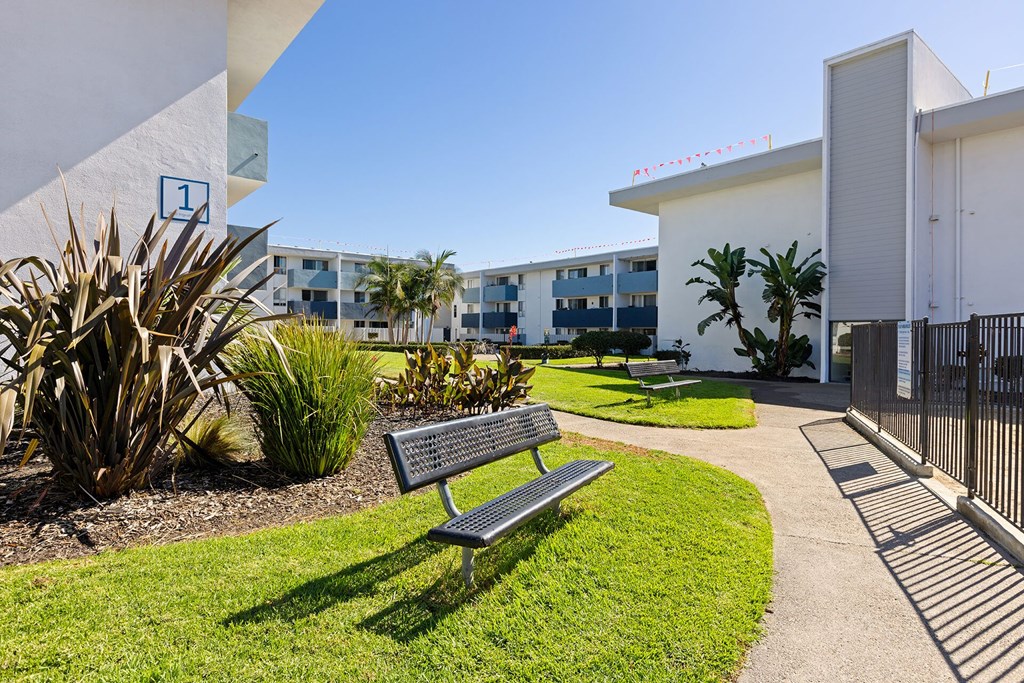 A bench is situated in a grassy area in front of a building.