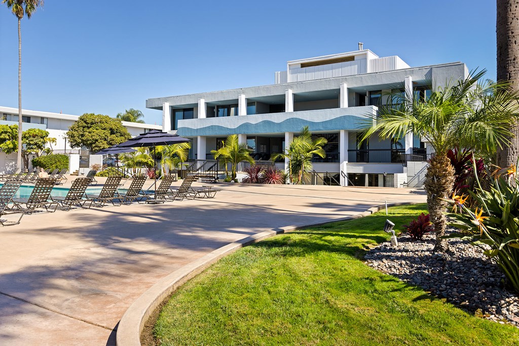 A modern building with a pool and palm trees in front.