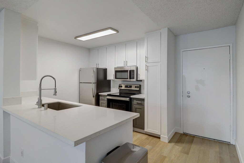 A kitchen with white cabinets and appliances.