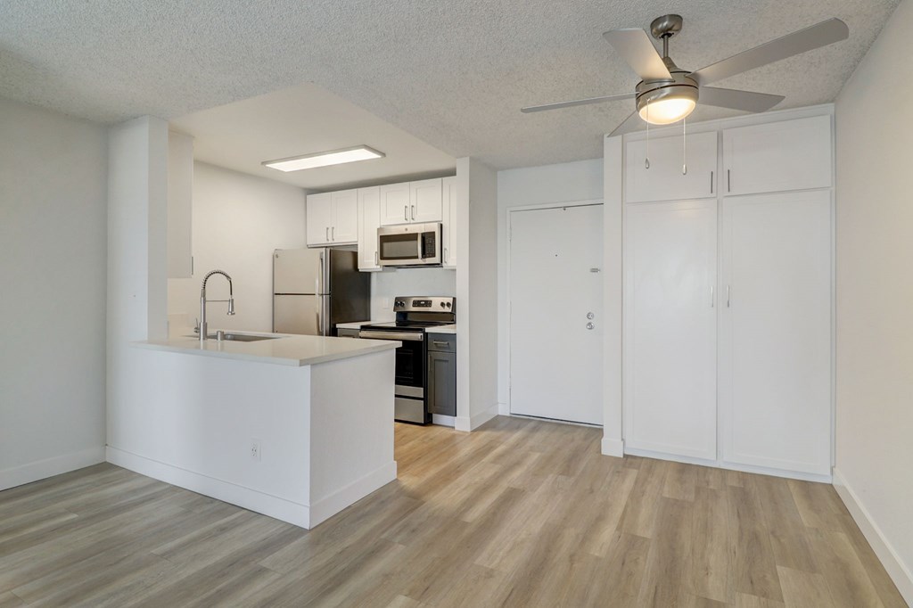 A kitchen with white cabinets and a wooden floor.