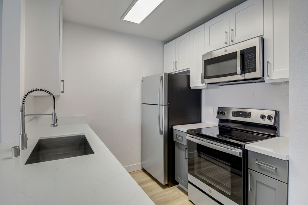 A kitchen with a sink, refrigerator, oven, and microwave.