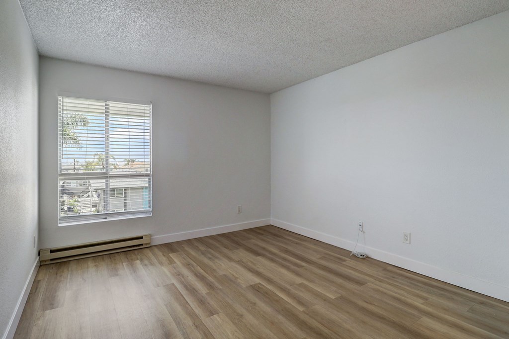A room with a window and wooden flooring.