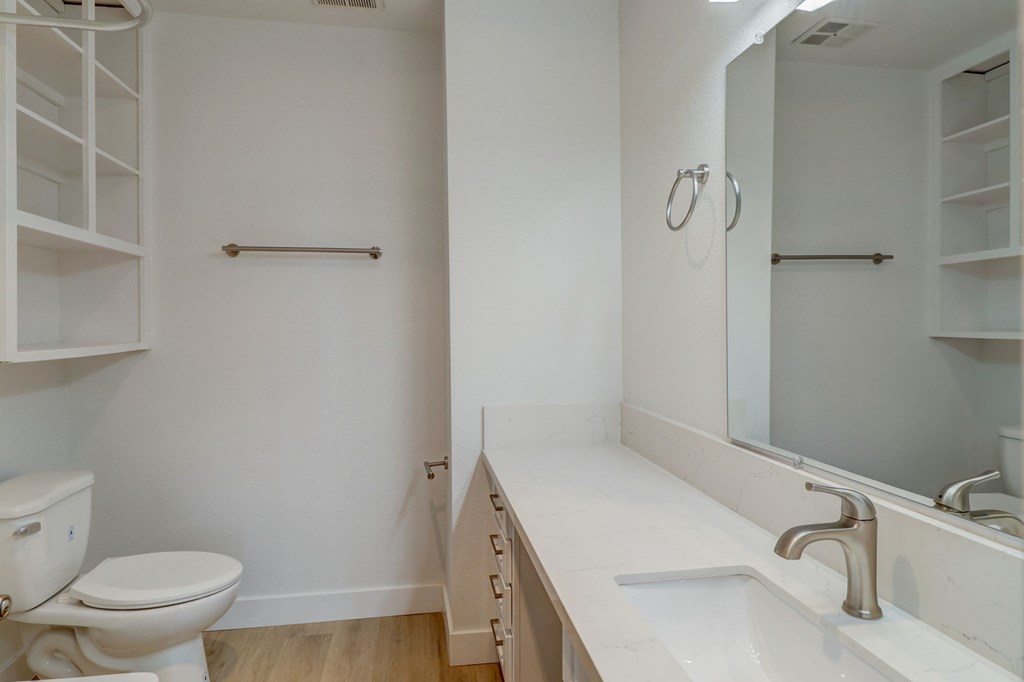 A white toilet sits next to a white sink in a small bathroom.