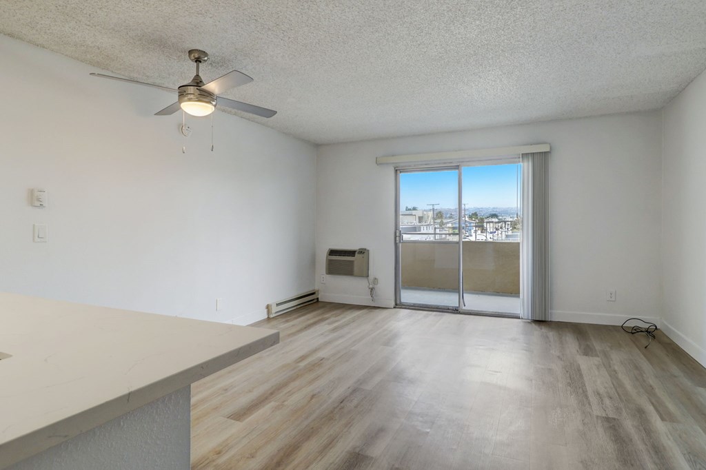 A room with a ceiling fan and sliding glass doors.