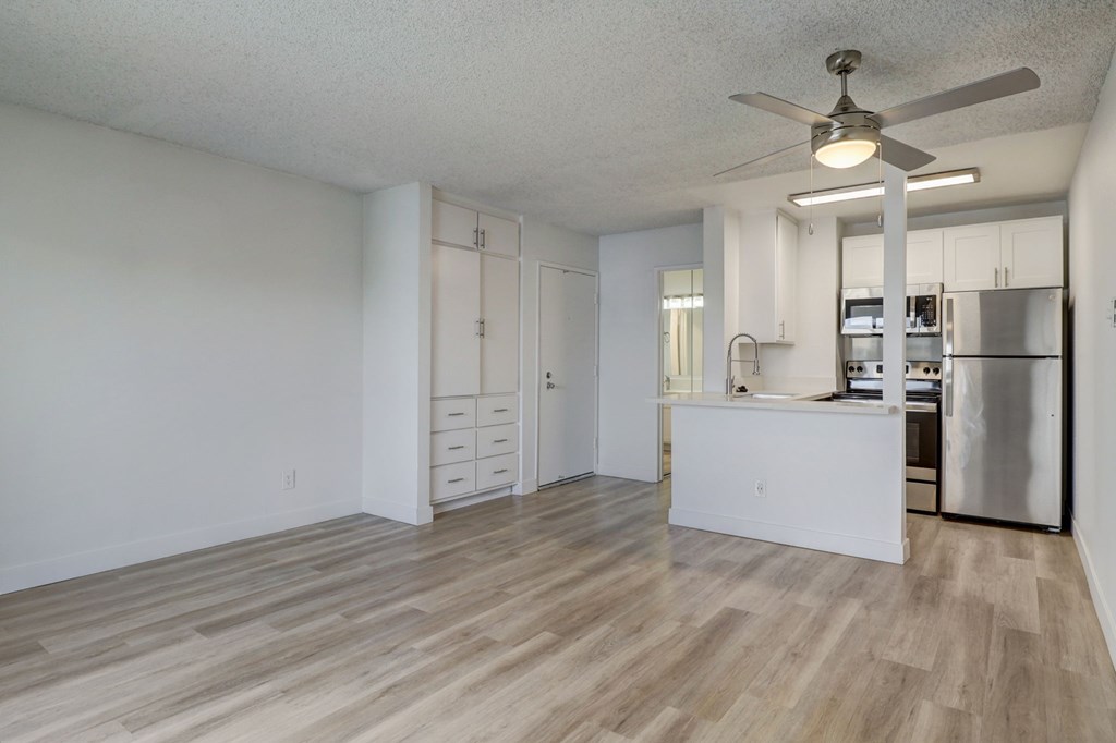 A kitchen with a refrigerator, stove, and cabinets.