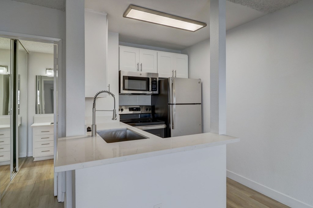 A modern kitchen with white cabinets and appliances.