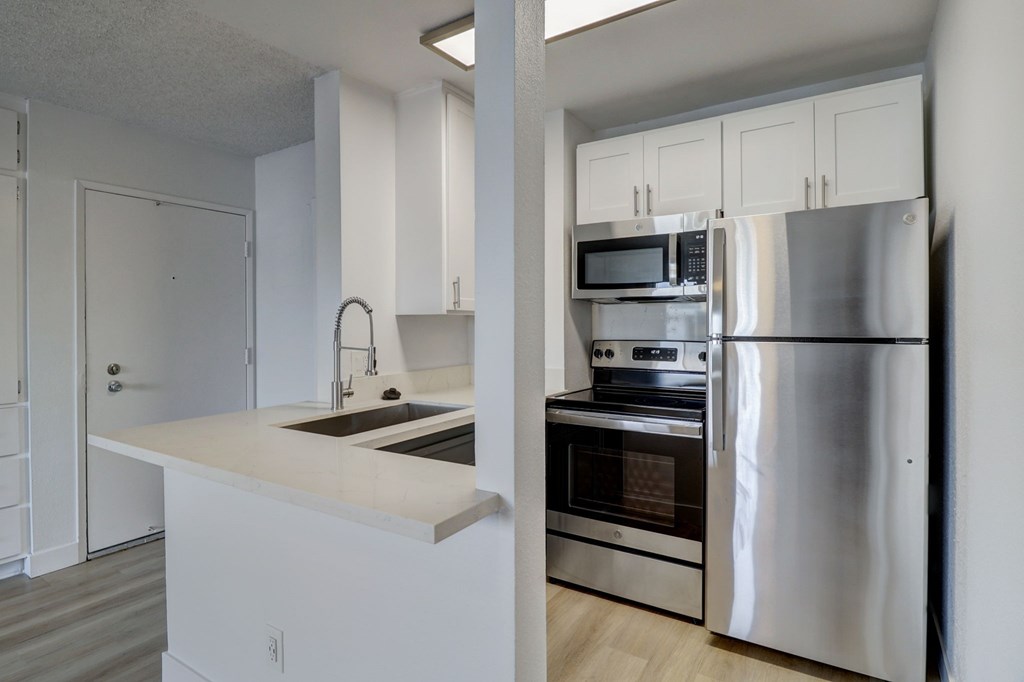 A modern kitchen with stainless steel appliances and white cabinetry.