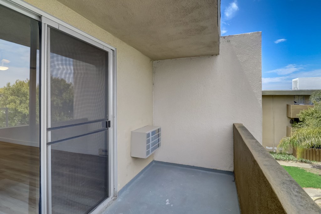 A balcony with a sliding glass door and a concrete wall.