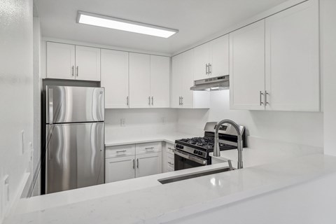 A modern kitchen with white cabinets and stainless steel appliances.