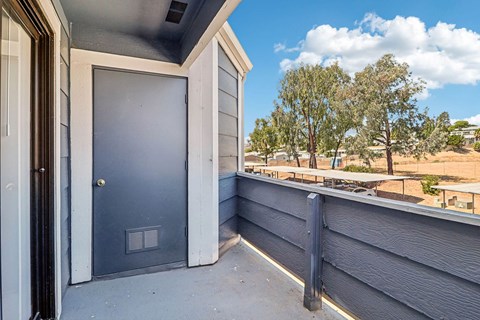 A blue door is on the left side of a grey house.