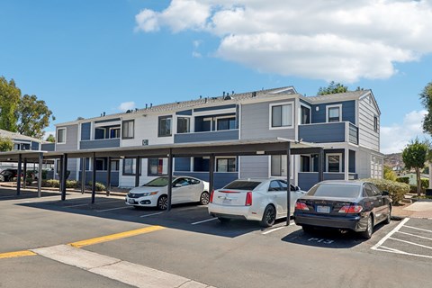 A parking lot with three cars parked in front of a building.