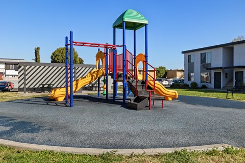 A playground with a yellow slide and a green roof.
