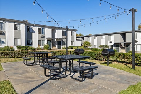 A black picnic table is in the middle of a concrete patio.