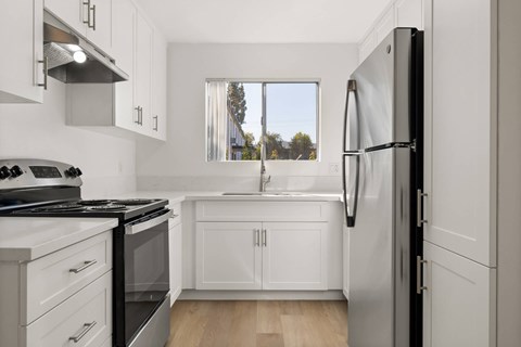 A modern kitchen with white cabinets and a black refrigerator.