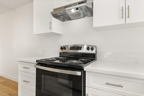 A modern kitchen with a stove top oven and white cabinets.