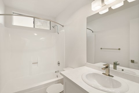 A white bathroom with a tub, toilet, and sink.