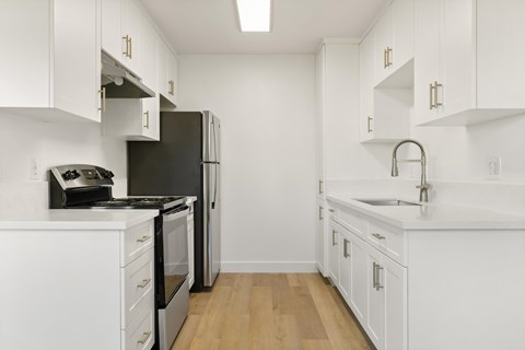 A kitchen with white cabinets and a black refrigerator.