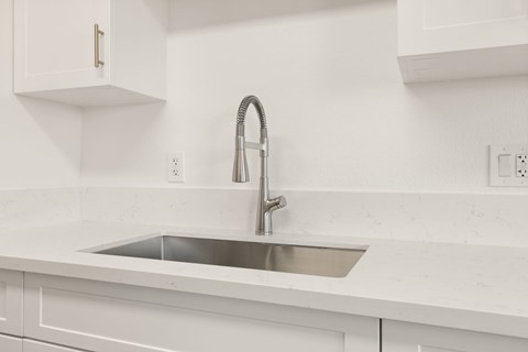 A modern kitchen with a white sink and faucet.
