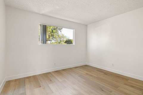 A room with a window and wooden flooring.