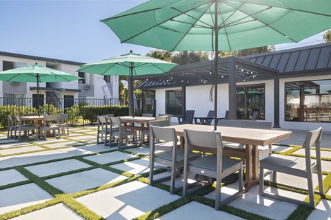 A patio with tables and chairs and umbrellas.