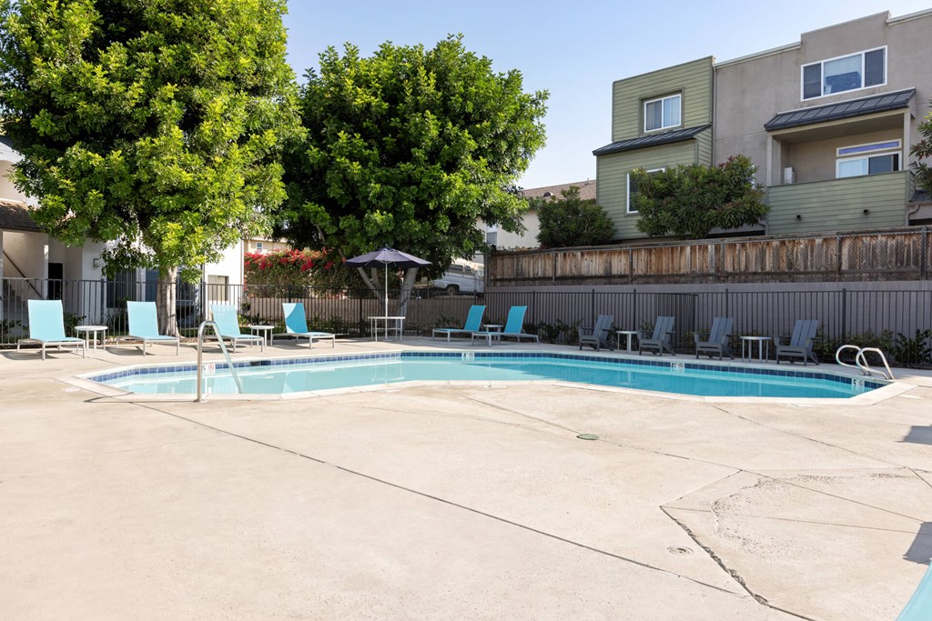 A swimming pool surrounded by trees and chairs.