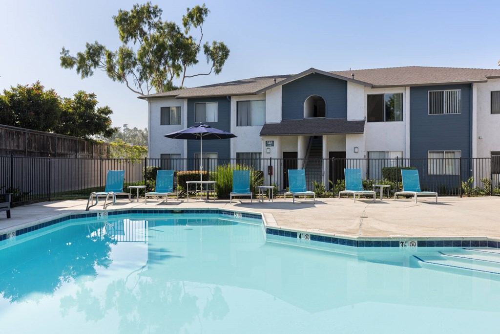 A swimming pool in front of a multi-story apartment building.