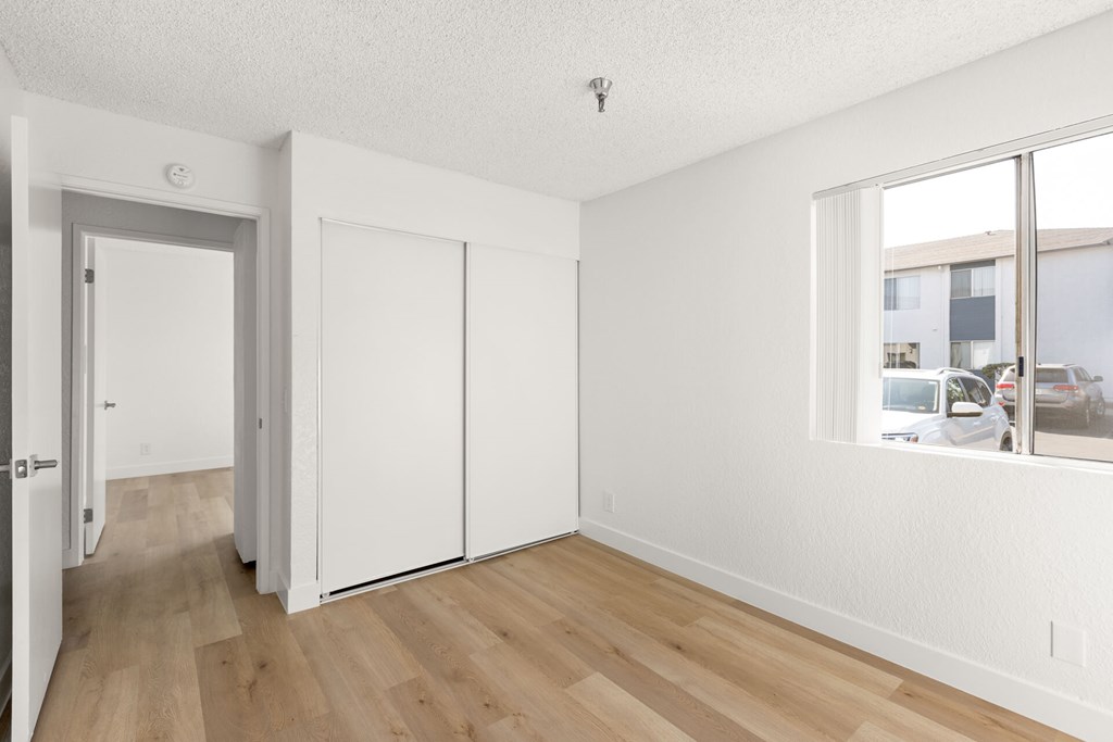 A room with a sliding door and a window overlooking a street.