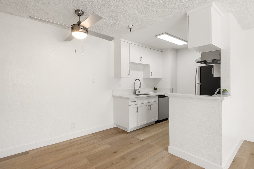 A kitchen with white cabinets and a black refrigerator.