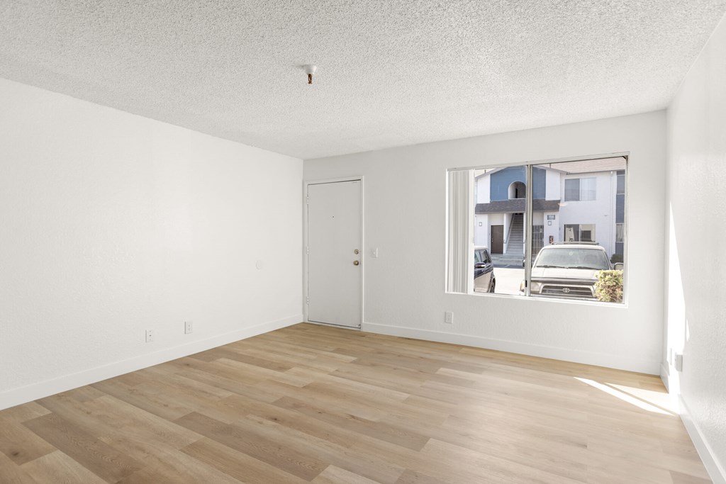 A room with a white door and a window showing a street view.