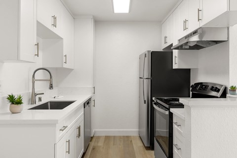 A modern kitchen with white cabinets and black appliances.