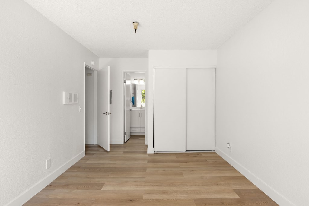 A long, narrow hallway with white walls and wooden flooring.