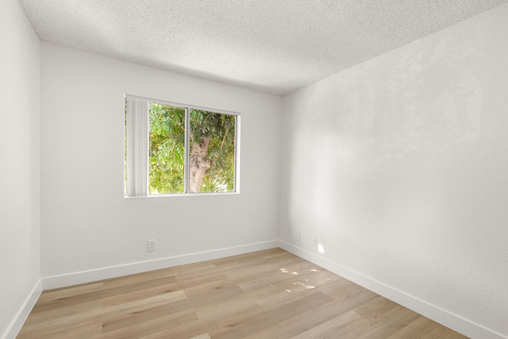 A room with a window and wooden flooring.
