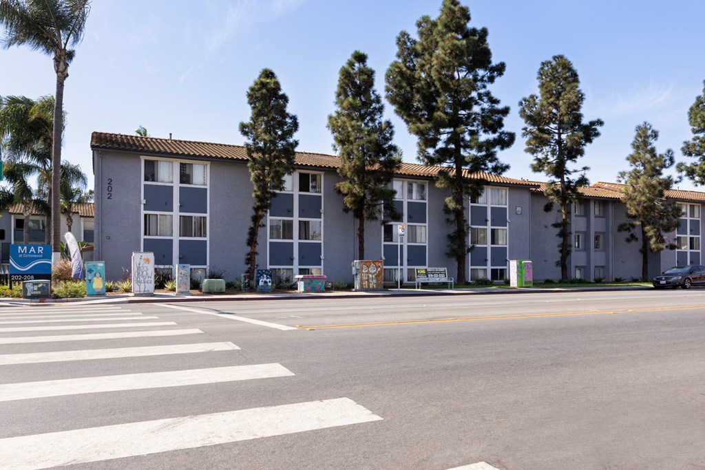 A street view of apartment buildings with a crosswalk in the foreground.
