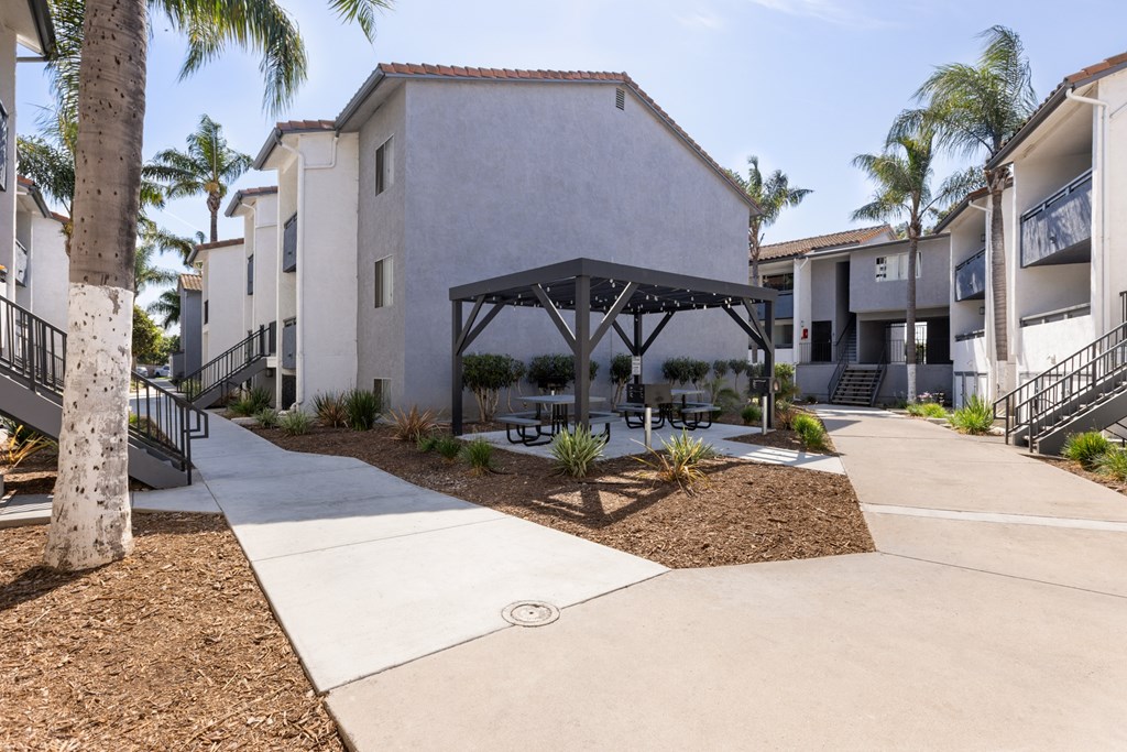 A building with a white exterior and a black roof is surrounded by palm trees.