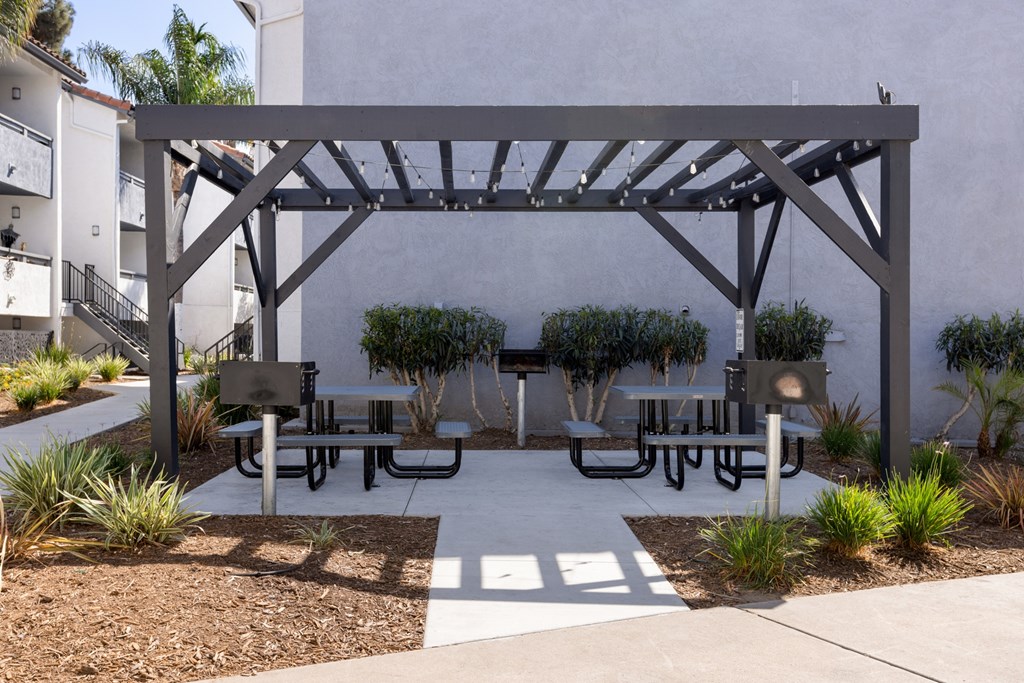 A pergola with benches is situated in a courtyard.