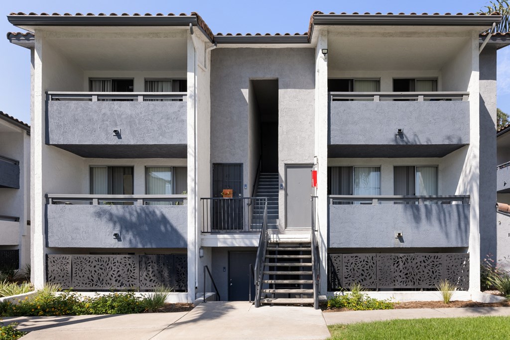 A two-story building with a balcony and stairs leading to the entrance.