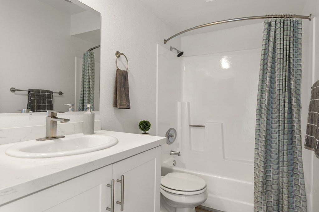 A white bathroom with a white toilet, sink, and shower.