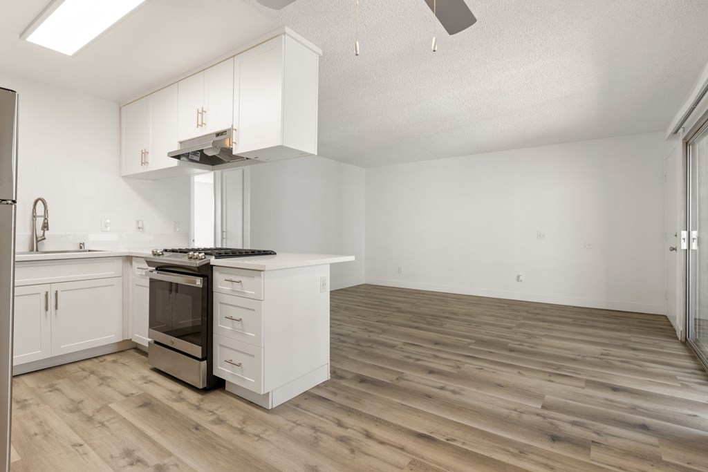 A kitchen with white cabinets and a wooden floor.