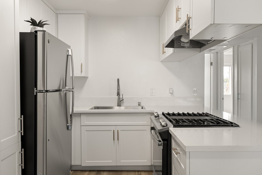 A black and white photo of a kitchen with a refrigerator, sink, and stove.
