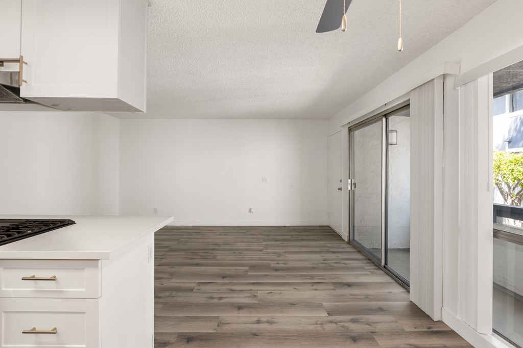 A kitchen with a white counter top and wooden floors.