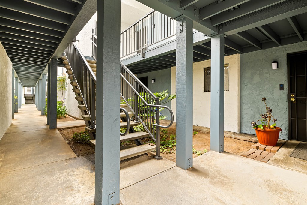 A long hallway with a staircase and pillars.