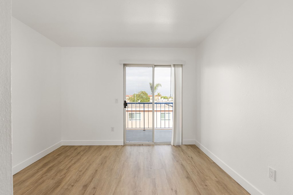 A room with a sliding glass door leading to a balcony.