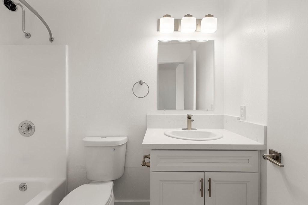A white bathroom with a toilet, sink, and mirror.