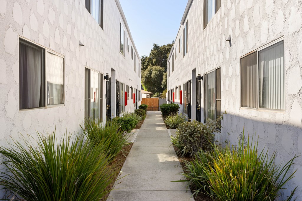 A white building with a patterned wall and a red door.