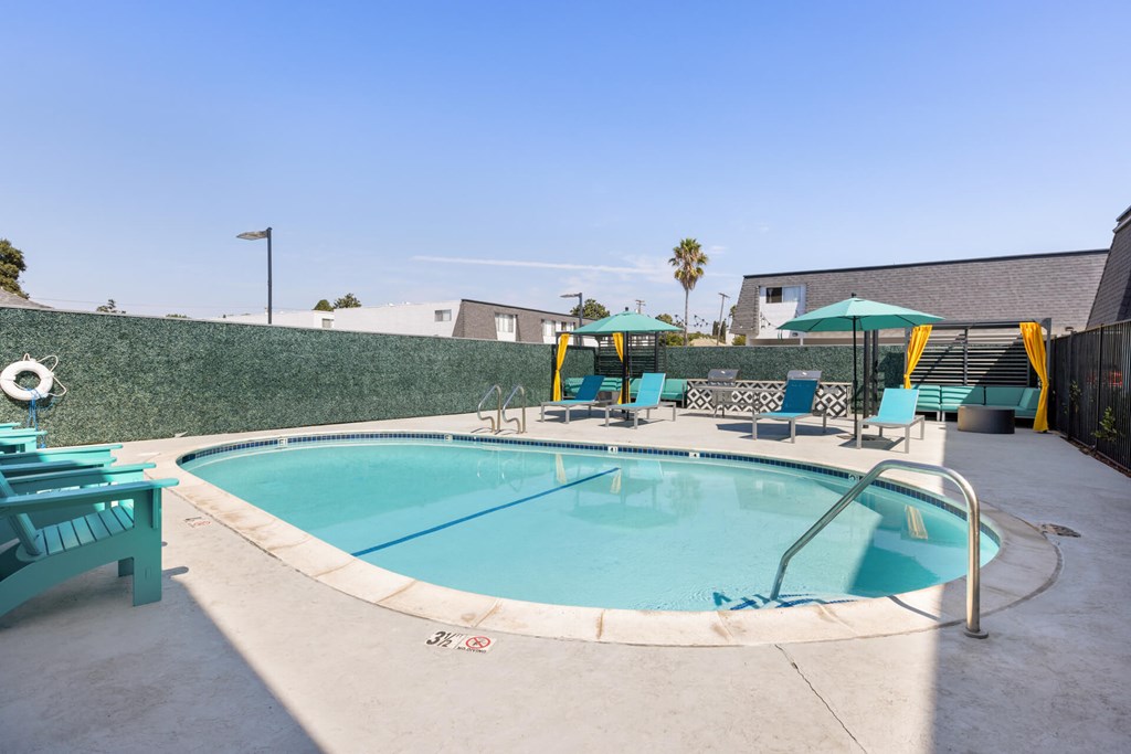 A small pool with a metal railing and a few chairs around it.