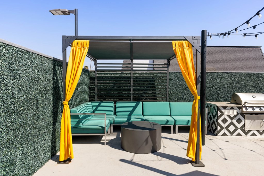 A patio area with a green couch and yellow curtains.