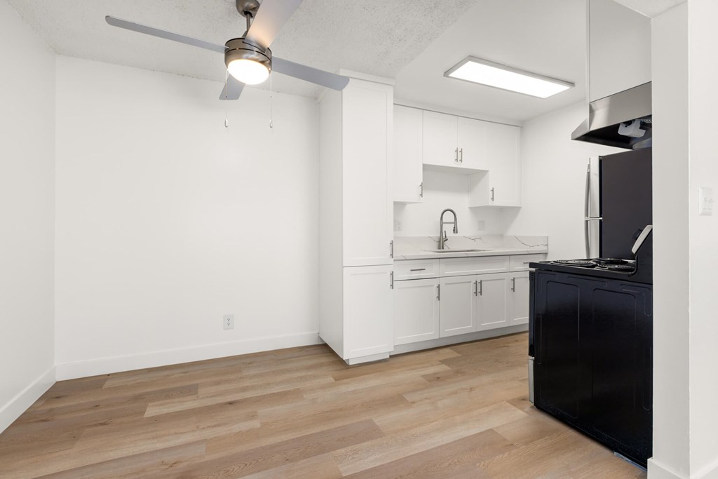 A kitchen with white cabinets and a black counter.
