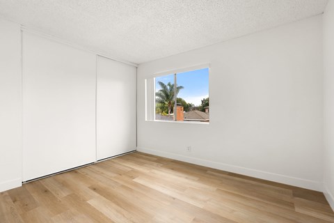 A room with a window showing a view of a building and trees outside.